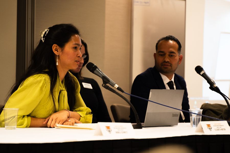 Panelists at a table with a microphone speak